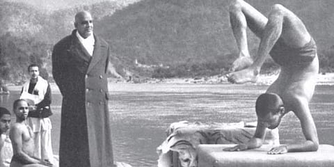 Swami Sivananda observes Swami Vishnudevananda doing the scorpion pose