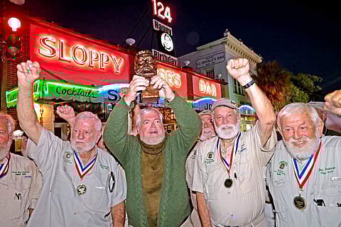 Gerrit Marshall, center, hoists his trophy after winning the Hemingway Look-Alike Contest
