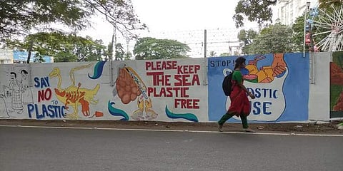 A girl walks past a wall adorned with the murals of art students. (Photo | A Sanesh)
