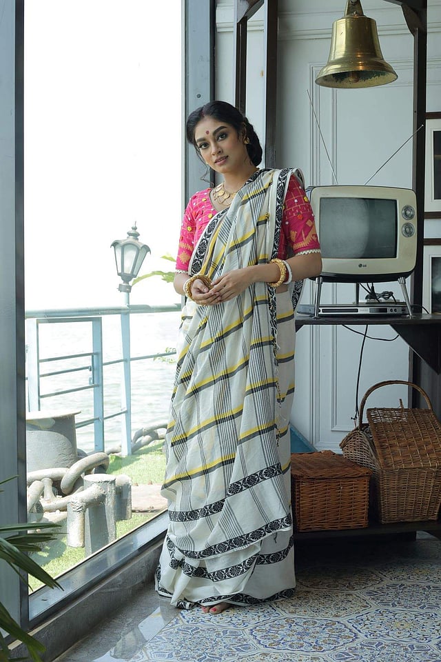 <em>A hand-woven striped cotton sari with a contrasting embroidered blouse, both by Parama Ghosh and guinea necklace and studs and Golap bala by A Sirkar</em>